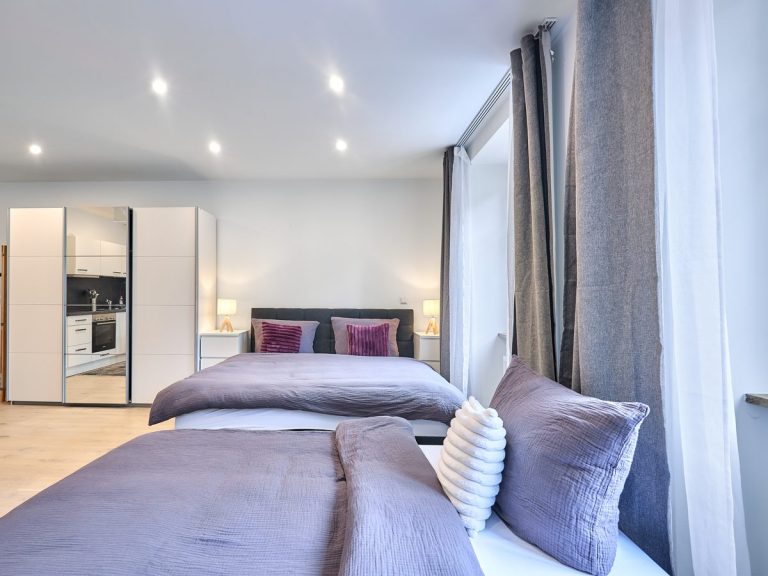 seeglueck | Münsterzauber | zentral 10 Boxspringbett mit Schlafsofa und violetten Akzenten im Schlafzimmer