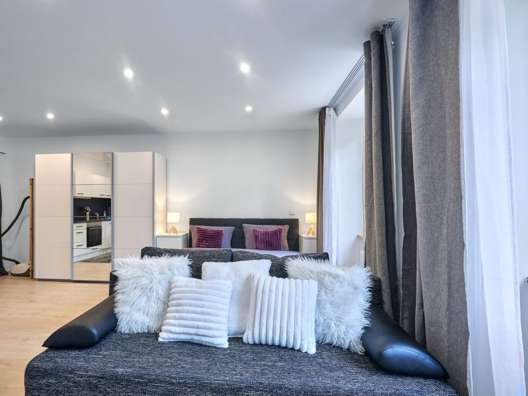 seeglueck | Münsterzauber | zentral 3 Graues Sofa im Wohnbereich des Appartements Münsterzauber mit Blick zum Schlafbereich